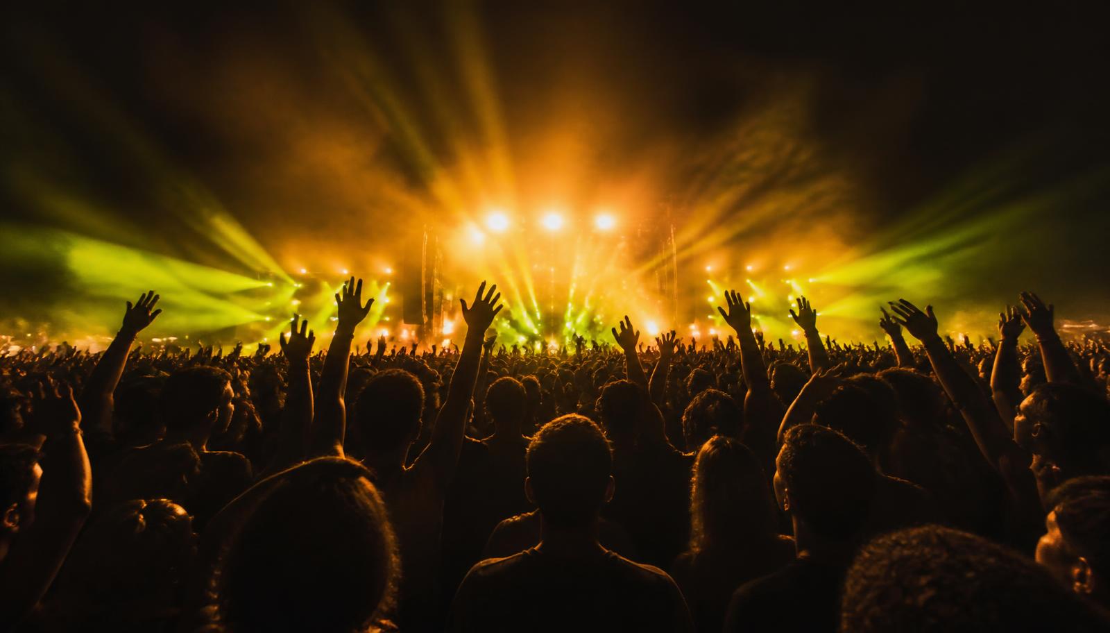Festival crowd with raised hands in front of a lit stage